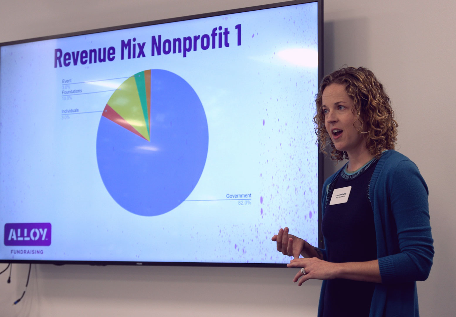 Speaker beside a revenue mix presentation, published by Alloy